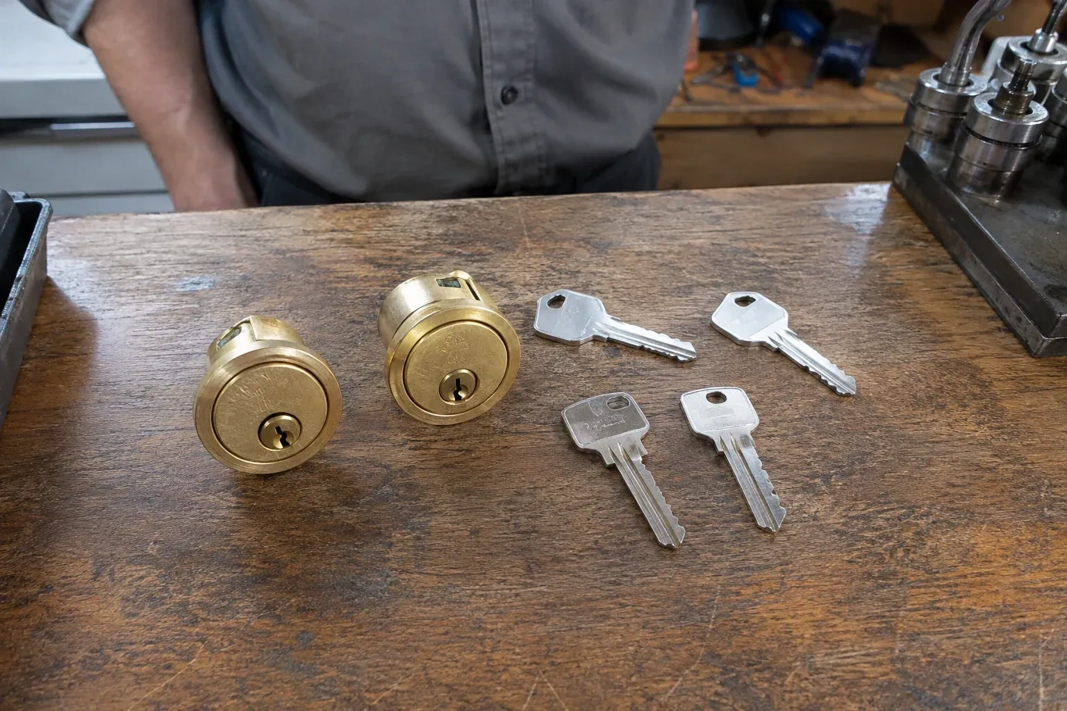 Two detached brass lock cylinders and four house keys on a wooden counter. — Lock Rekeying, London